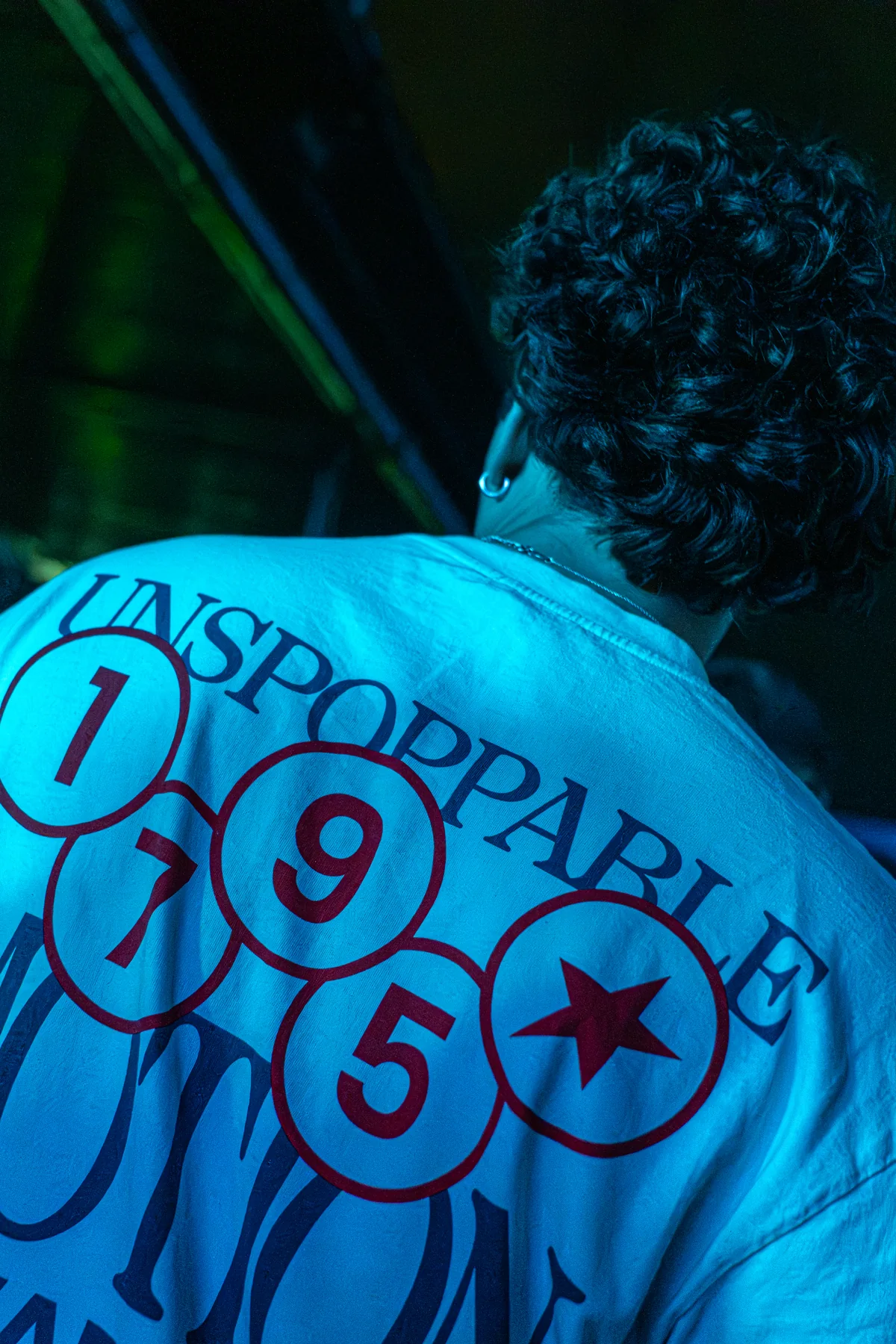 Un chico de espaldas con una camiseta estampada bajo luz azul