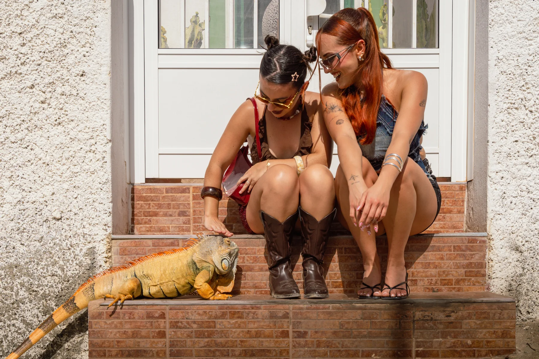 Dos protagonistas sentadas en una escalinata con una iguana