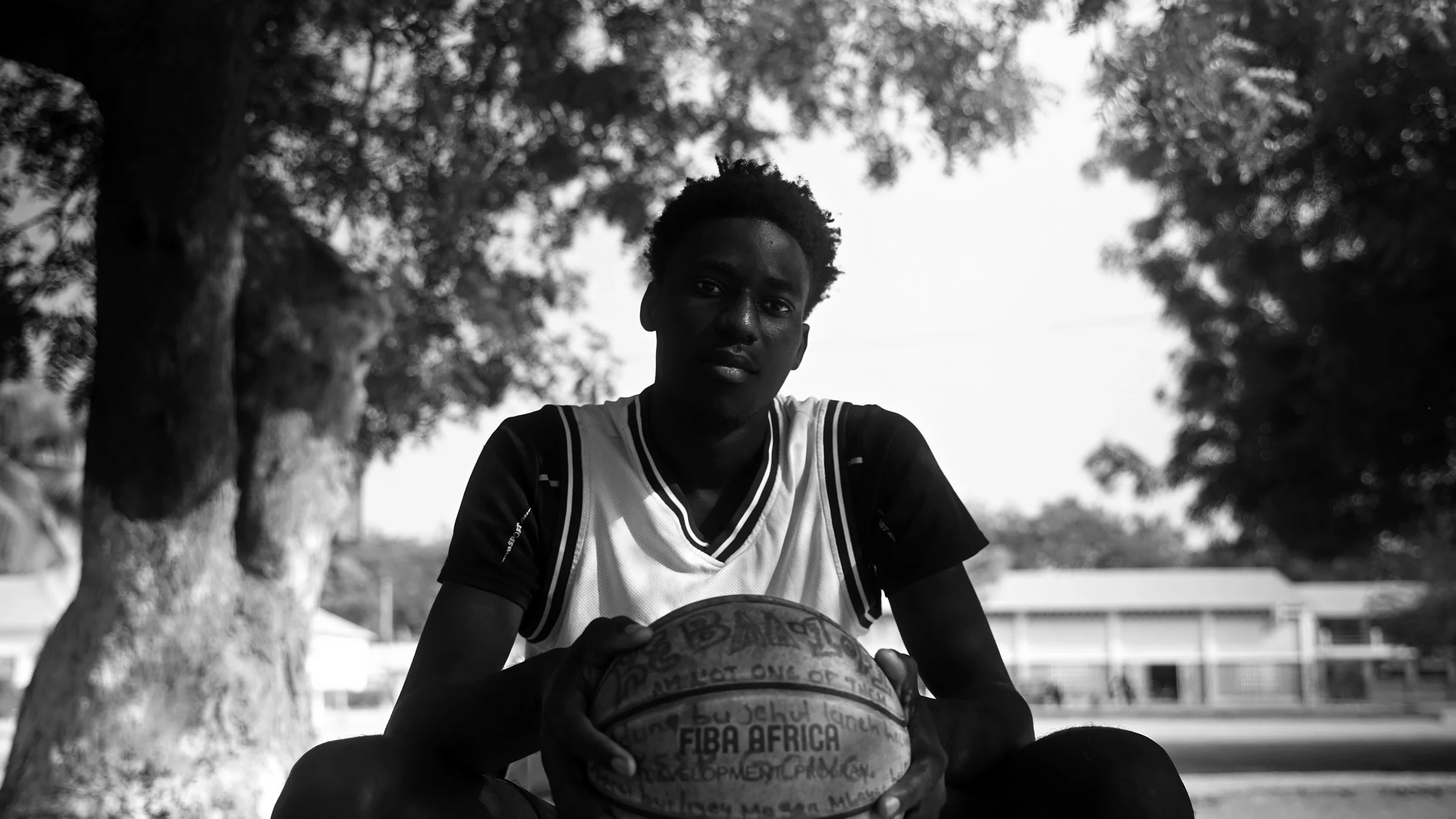 Joven jugador sentado con un balón FIBA Africa
